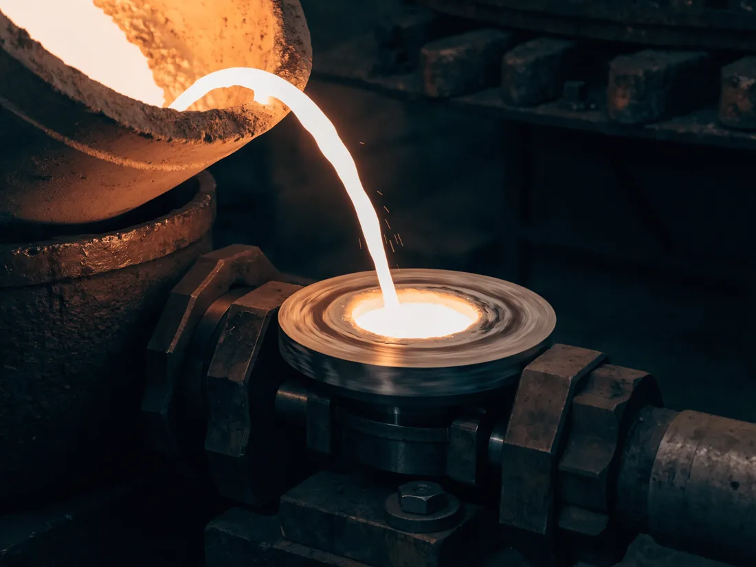Molten white metal being poured into a rotating bearing shell during spin casting